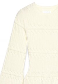 Adīts garām piedurknēm džemperis gaiši dzeltenā krāsā, ar ribota raksta un savērpuma detaļām pa rokām un ķermeni, kas nodrošina mājīgu izskatu.