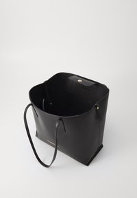 Zwarte leren tote bag met een gestructureerde vorm, voorzien van twee lange handvatten en een gouden drukknoopsluiting. Het interieur heeft een gladde textuur.