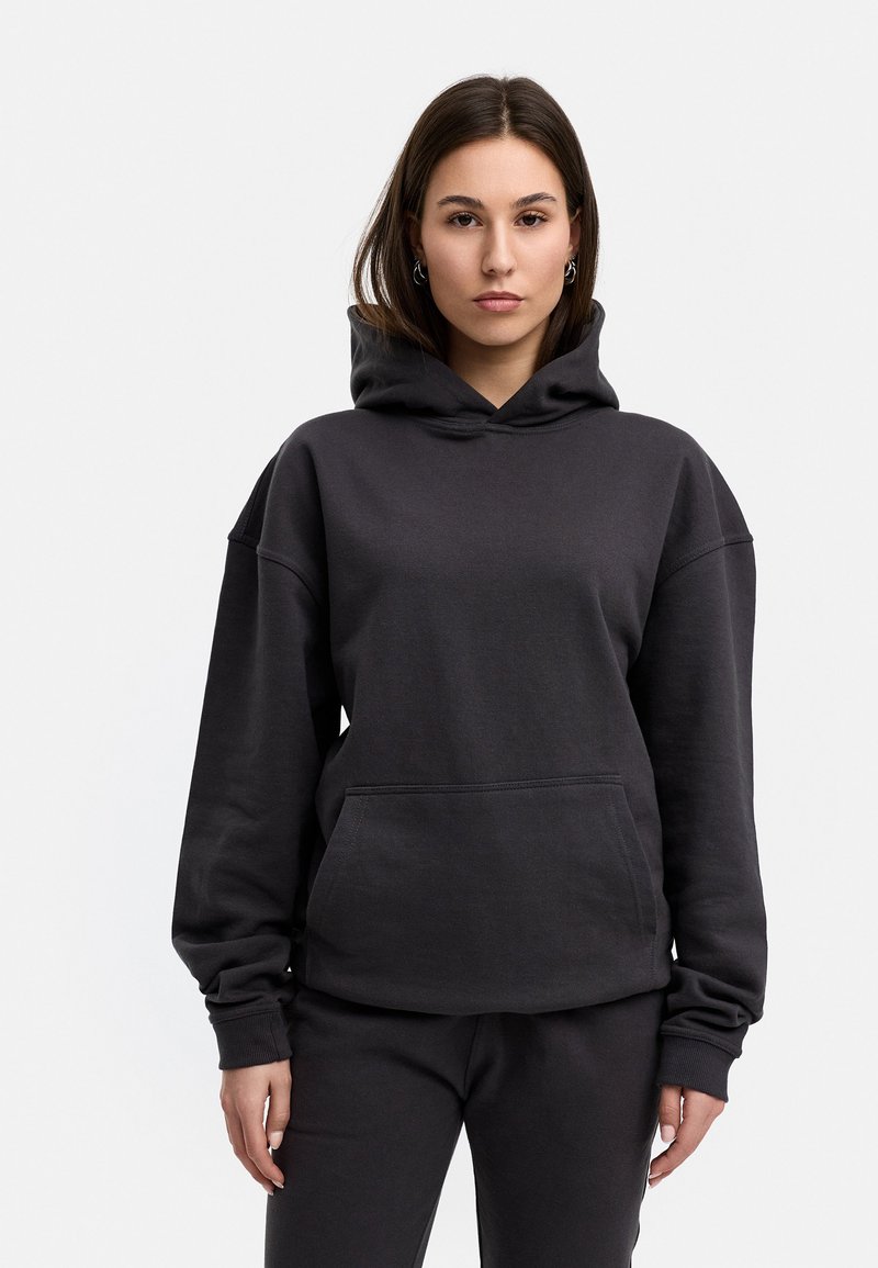 Schwarzes, übergroßes Hoodie aus Baumwollmischung mit einer Fronttasche und verstellbarem Kordelzug an der Kapuze. Glatte Textur, lässige Passform.