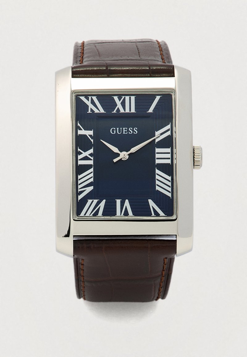 Reloj cuadrado de metal plateado con esfera azul texturizada, números romanos y correa de cuero marrón con patrón de cocodrilo.