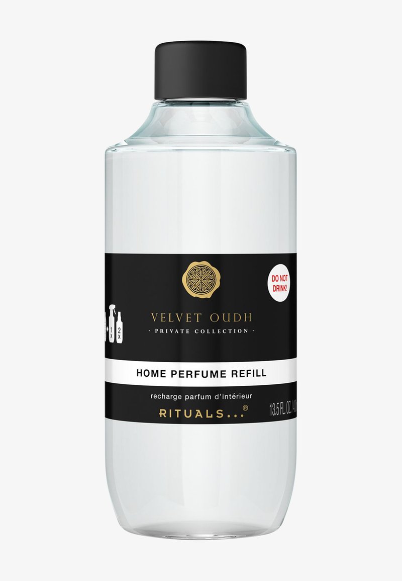 Bottiglia di vetro trasparente con tappo nero. Presenta un'etichetta in bianco e nero con dettagli dorati, che indica "Ricarica di Profumo per Ambienti Velvet Oudh".