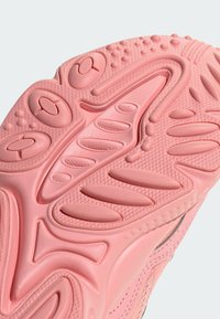 Suola di sneaker rosa con design in gomma testurizzata caratterizzata da motivi vari, inclusi elementi circolari e ondulati per una migliore aderenza.