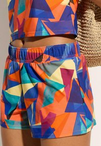 Shorts sportivi dai colori vivaci in arancione, blu, giallo e viola. Vita elastica con tasche laterali. Tessuto leggero e liscio.