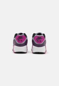 Nike Air tenisice s crnim gornjim dijelom, ljubičastim i ružičastim akcentima, teksturiranim petnim dijelom i bijelim potplatom. Dizajn naglašava udobnost i potporu.