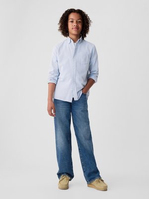 Lyseblå skjorte med lange ærmer, parret med vidde jeans i blå farve og beige mokkasinstil sko. Enkel design, afslappet look.