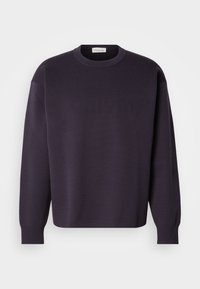 Sweat-shirt à col rond couleur violet foncé avec manches longues, logo texturé subtil sur le devant, poignets et ourlet côtelés. Matière douce et tricotée.