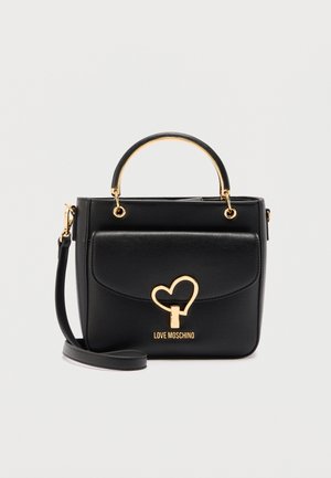 Sac à main Moschino Black Love avec fermoir en forme de cœur doré, poignée supérieure et bandoulière amovible sur fond blanc uni.