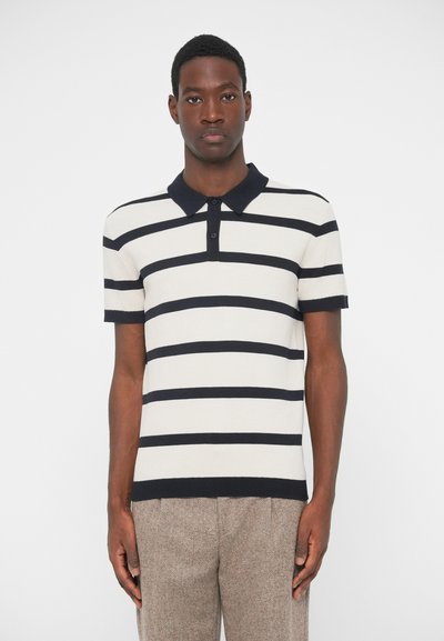 Camisa polo a rayas en crema y azul marino. Cuenta con un cuello, mangas cortas y una tapeta de botones. Tejido texturizado con un diseño ajustado.
