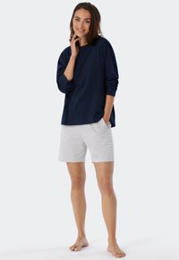 Marinblå långärmad topp i mjukt tyg, kombinerad med ljusgrå shorts. Shortsen har en avslappnad passform och sidofickor.