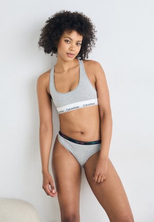 Sivá bavlnená športová podprsenka s bielym pásom Calvin Klein a zodpovedajúcim sivým tangom s multikolórovým pásom. Jednoduchý, priliehavý dizajn.