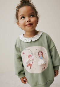 Grøn sweatshirt med en struktureret hvid krave, prydet med en trykt illustration af en dreng og en pige med gyldne accenter og stjerner.