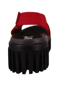Sandale plateforme rouge avec une semelle texturée, une large bride et un dos arrondi. Présente une épaisse semelle noire avec des rainures verticales.