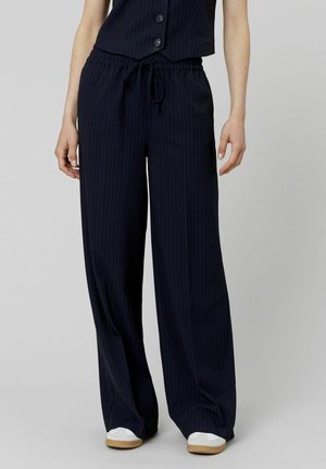 Pantalons rayés bleu marine avec une coupe décontractée, dotés d'une taille élastique et d'un cordon de serrage. Fabriqués en tissu doux avec une texture lisse.