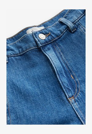 Džinsai su aukštu liemeniu, vidutinio mėlynumo spalvos, su vario siūlėmis, metaliniu mygtuku ir klasikine užtrauktuko uždarymo sistema.