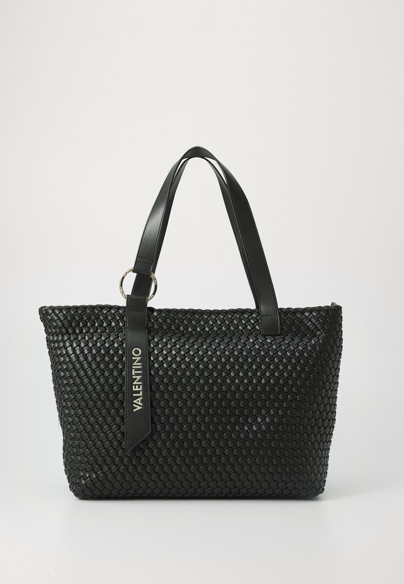 Black woven tote bag featuring a smooth leather strap, a metal ring accent, and a logo tag. Textured pattern throughout the bag.