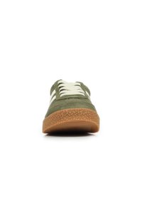 Sneaker verde in suede con strisce bianche, punta rotonda e suola in gomma gommata testurizzata. I lacci sono di colore crema e piatti.