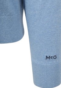 Light blue knit sweater featuring ribbed cuffs, with a small black "McG" logo on the left sleeve. Soft texture and classic design.