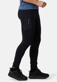 Schwarze Sportleggings mit schlankem Schnitt, ausgestattet mit einer seitlichen Reißverschlusstasche und aus flexiblem, feuchtigkeitsableitendem Material gefertigt.