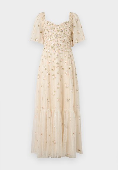 Robe maxi beige clair avec manches bouffantes, broderie florale, décolleté en cœur et jupe à volants semi-transparente avec des pois délicats.