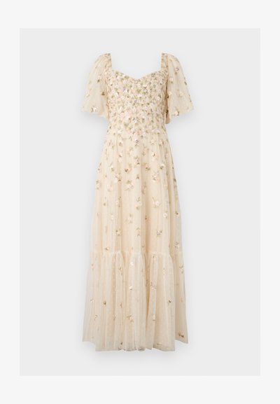 Robe maxi beige clair avec manches bouffantes, broderie florale, décolleté en cœur et jupe à volants semi-transparente avec des pois délicats.
