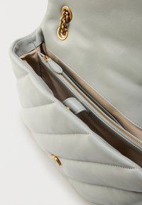 Γκρι ανοιχτό δερμάτινη τσάντα με ραφές, διακοσμημένη με χρυσή αλυσίδα, αποκαλύπτοντας εσωτερική τσέπη με φερμουάρ και λεία μπεζ επένδυση.