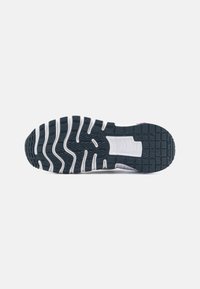 Svart og hvit sneakersåle med bølgemønster, gummiflate, støpte spor og en rosa aksent nær hælen.
