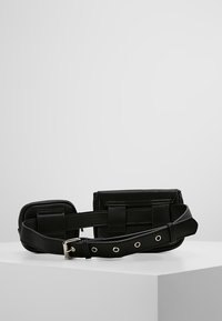 Sac banane en cuir noir avec un compartiment principal rectangulaire et deux petites poches latérales. Présente une texture lisse et des accents en métal argenté.