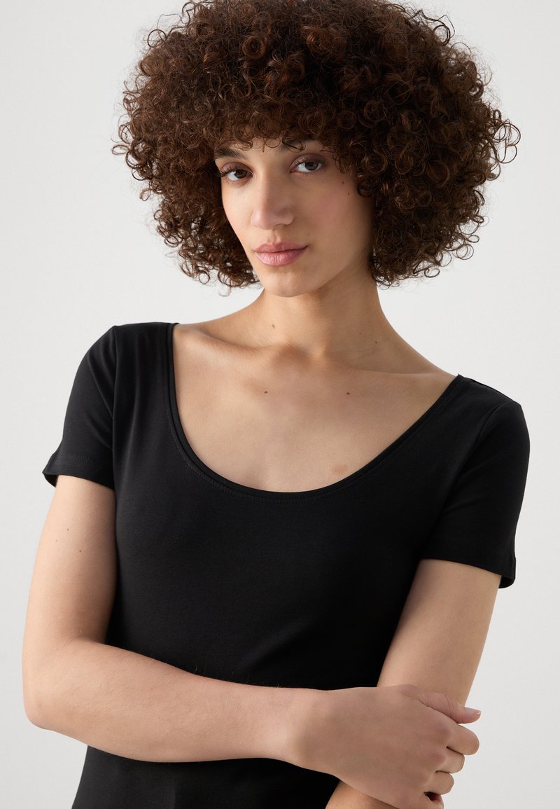 T-shirt noir à manches courtes avec un décolleté en forme de bateau, fabriqué à partir d'un tissu doux et lisse. Présente un design ajusté, mettant en avant un look propre et minimaliste.