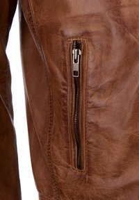 Bruine leren jas met een zijritszak. Gelaagd oppervlak met een versleten uitstraling. Robuuste metalen hardwaredetails.