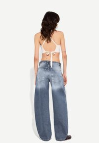 Jeans med vida ben i ljusblått med en blekt finish, med medelhög midja och stora bakfickor. Matchas med en vit kort topp.