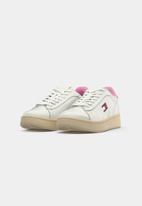 Vita lågskor i sneakerstil med beiga sulor, rosa foder, vita snörningar och en liten Tommy Jeans-logotyp på sidan.