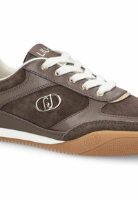 Baskets marron en matériaux lisses et en daim. Elles comportent des lacets blancs, un accent de logo argenté, et une semelle extérieure en gomme texturée.