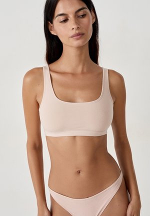 Bralette seamless rosa chiaro con scollo quadrato, spalline larghe e texture morbida, abbinata a slip a vita bassa coordinati.