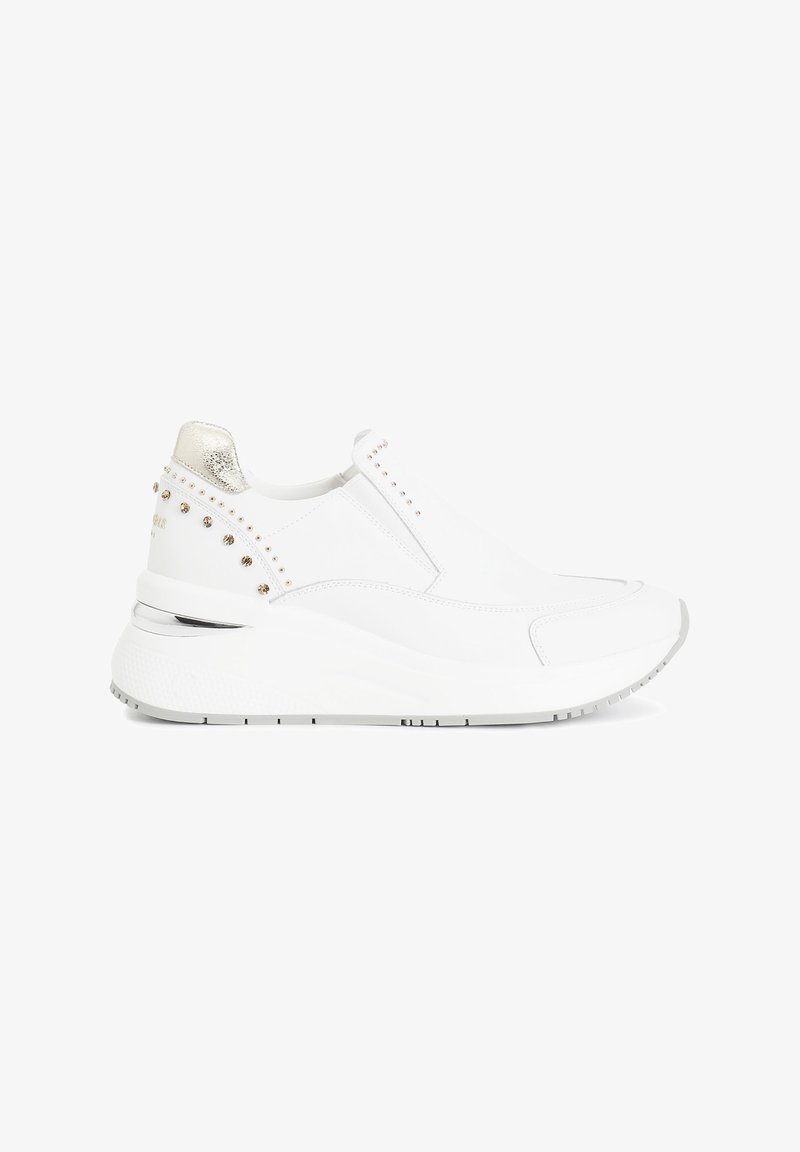 Zapatillas blancas sin cordones con parte superior texturizada blanca, acentos metálicos dorados en el talón y tachuelas decorativas a lo largo del costado. Suela gruesa para mayor amortiguación.