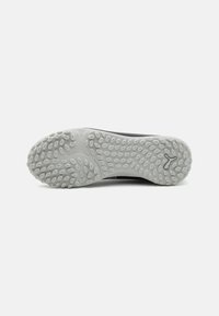 Schuhsohle mit einer strukturierten Gumm Oberfläche, die ein kreisförmiges Muster und ein zentrales Logo aufweist. Überwiegend grau mit einem schwarzen Akzent.