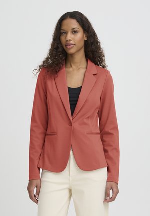 Blazer in roestkleur met een getailleerde pasvorm, opstaande kragen, twee voorkanten zakken en een enkele knoopsluiting, gecombineerd met een zwart topje.