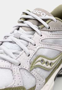 Sneaker med overdel i mesh og suede-overlays i lysegrå og olivengrøn, med hvide snørebånd og logo detaljer på tungen.