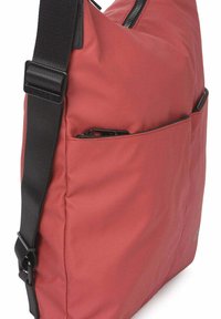 Rode nylon boodschappentas met een zwarte verstelbare riem, een ritssluiting bovenaan en een voorvak. Compacte vorm met een gladde textuur.