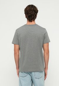 Szürke pamut póló kerek nyakkal és rövid ujjakkal, egyszerű mintával. Az anyag sima, laza szabású.