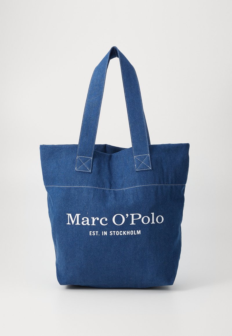Denim-Tragetasche mit zwei stabilen Griffen, versehen mit dem weißen Drucktext "Marc O'Polo EST. IN STOCKHOLM" und kontrastierenden Nähten.
