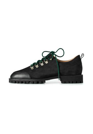 Zwarte suède schoenen met een ronde neus, groene veters, zilveren ooggaten en een robuuste zwarte zool met een gestructureerd patroon.