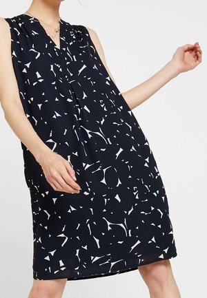 Marineblaues Kleid mit V-Ausschnitt und ärmellosem Design. Verziert mit einem abstrakten weißen Muster verschiedener Formen. Leichter, fließender Stoff.