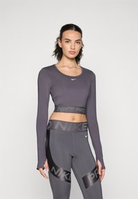 Gray long-sleeve sports crop top with a round neck, paired with matching high-waisted leggings featuring a "Nike Pro" logo band.