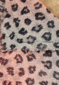 Tkanina w zwierzęce wzory z mieszanką szarości i koralu, z czarnymi plamami i frędzlami, prezentująca miękkie, teksturowane wykończenie.
