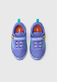 Μωβ παπούτσια με επάνω μέρος από δίχτυ, ελαστικά κορδόνια και ι μάντα με βέλκρο. Διαθέτουν πράσινη και μπλε πατημένη σόλα με σχέδιο και κόκκινο λογότυπο στην εσωτερική σόλα.