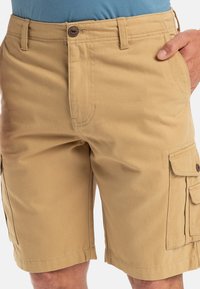 Khaki cargo šortky vyrobené z materiálu s obsahem bavlny. Mají několik kapes, zapínání na knoflík a zesílené švy. Hladká textura.