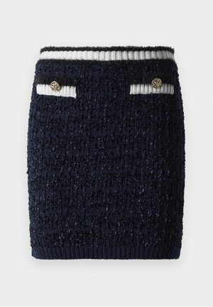 Navy blue textured mini skirt with ribbed white and navy striped waistband and two small front pockets, each with a gold decorative button.