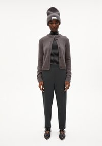 Grijze wollen cardigan met knopen, gestreepte coltrui, donkere broek en grijze gebreide muts. Bevat spitse schoenen met gespsieraden.