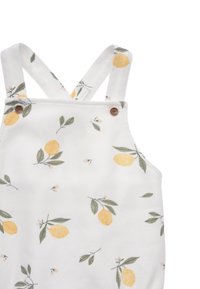 White fabric romper with yellow lemon and green leaf print. Features adjustable crossback straps and brown button accents. Soft texture.
