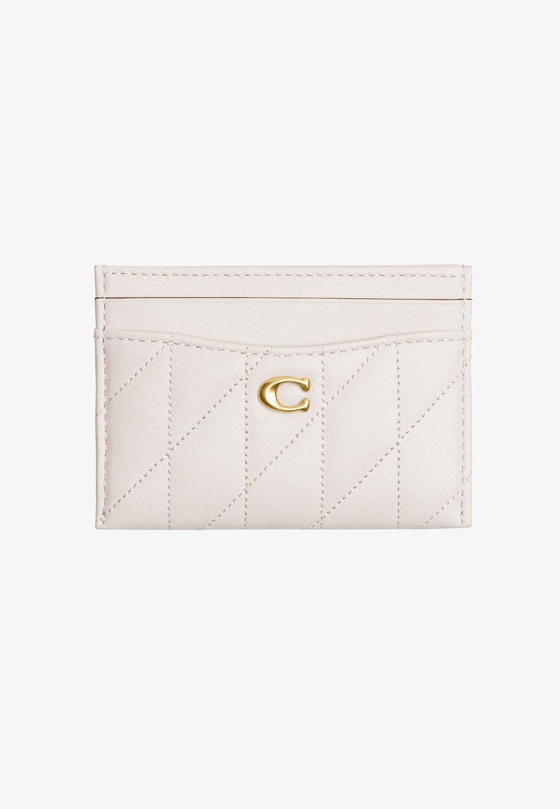 Porte-cartes en cuir blanc avec couture matelassée diagonale et un petit emblème en forme de lettre C dorée sur la poche avant centrale.